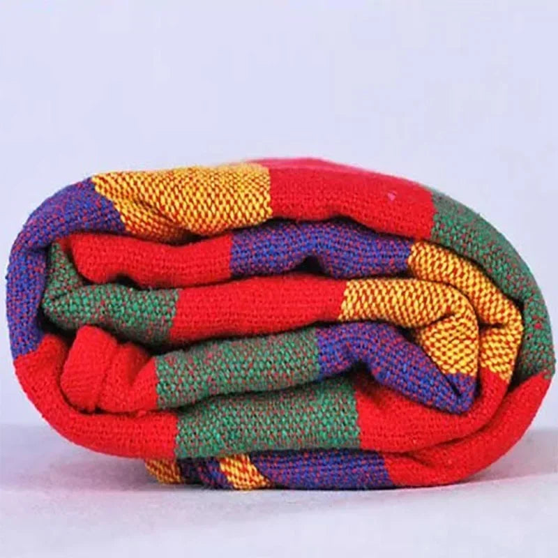 Colorful knitted blanket with red, yellow, blue, and green pattern on a white background