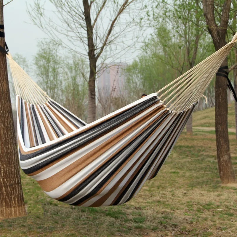 Striped hammock hanging between two trees in a park setting