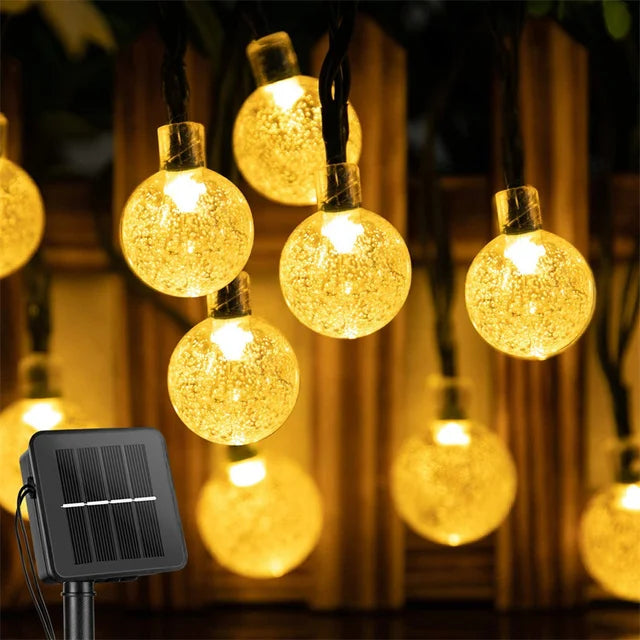 String of decorative lights with a solar panel power source, glowing warmly.