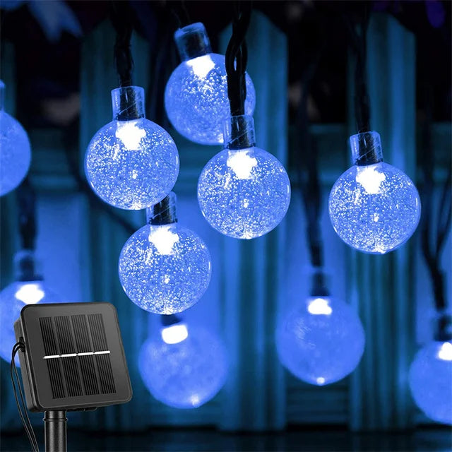 String of blue LED lights with a solar panel power source, glowing in the dark.