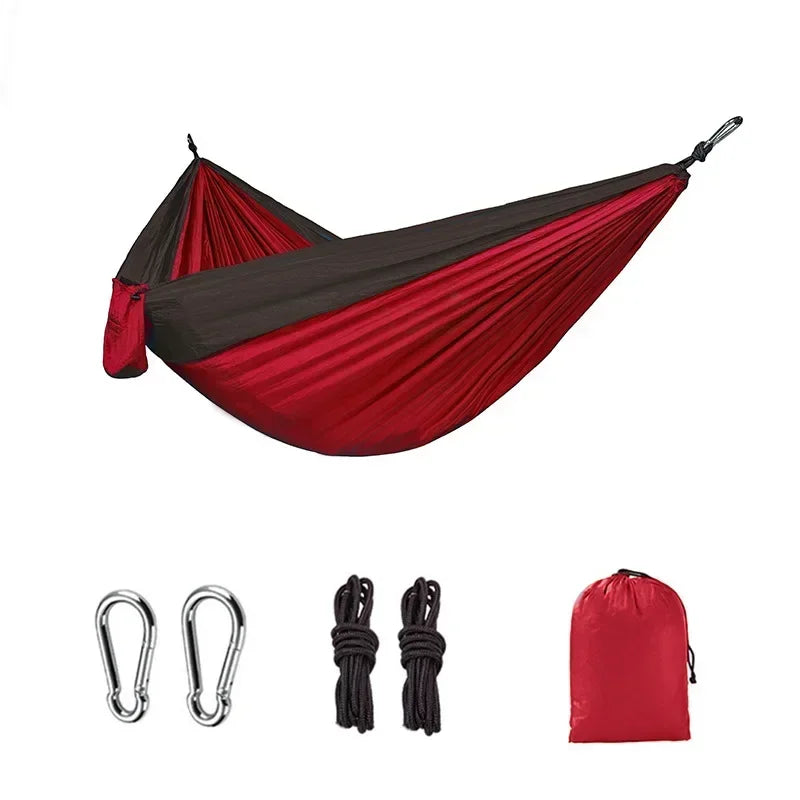 Red and black hammock set with carabiners, ropes, and carrying bag on a white background