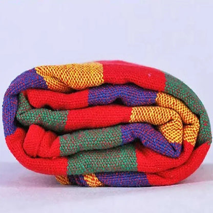 Colorful knitted blanket with red, yellow, blue, and green pattern on a white background