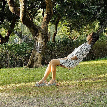 Person relaxing in a hammock under a tree in a park