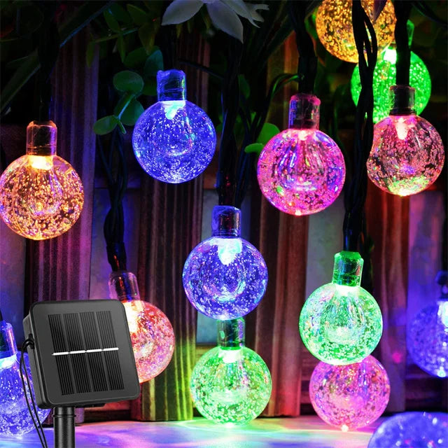 Colorful crystal ball string lights with a solar panel on a dark background
