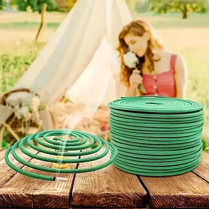 Green incense coils on a wooden surface with a blurred background of a woman and tent.