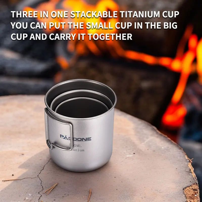 Stackable titanium cups on a rock with a campfire in the background