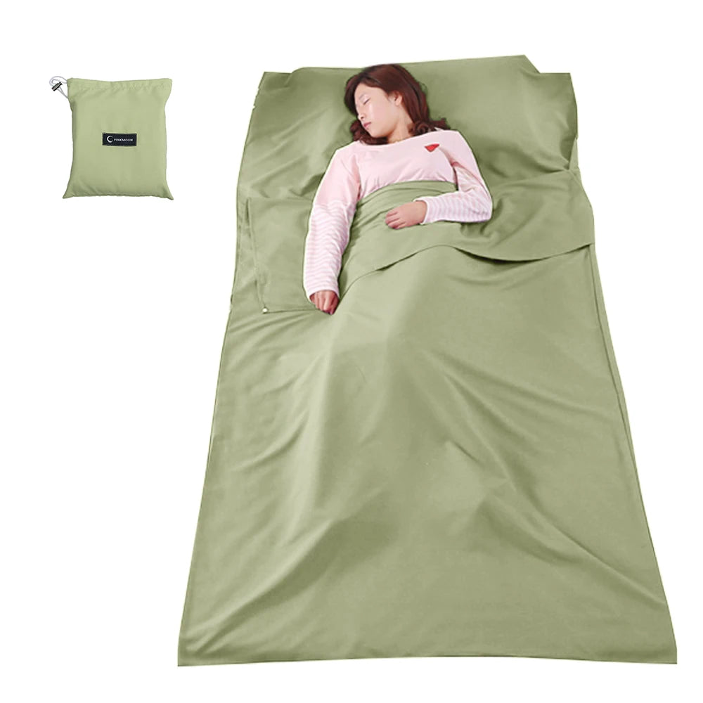 Person lying in a green sleeping bag with a matching pillow on a white background