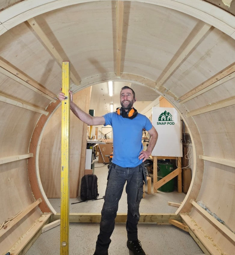 Sam,the founder of snappod Uk standing inside a glamping pod worrking in progress
