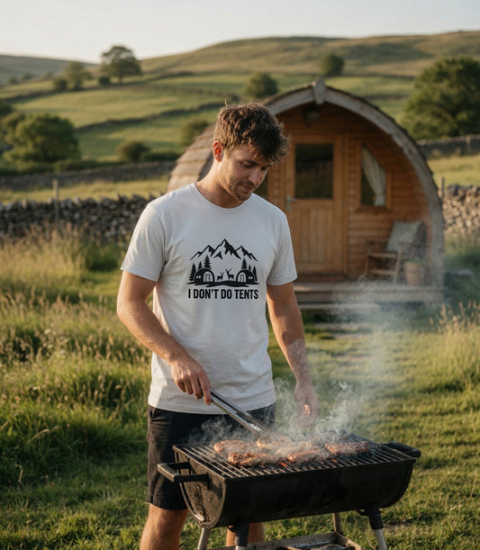 Man grilling outdoors in a scenic rural setting wearing a t-shirt with text.